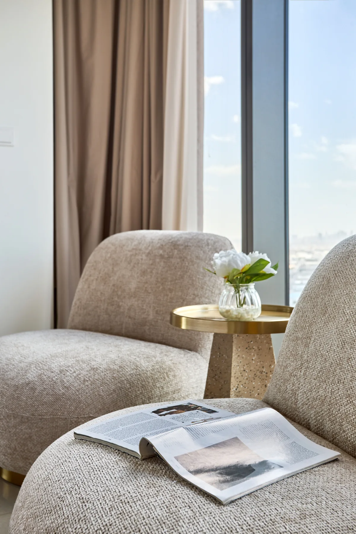 A bright seating area beside a large window, with an open magazine on the seat.