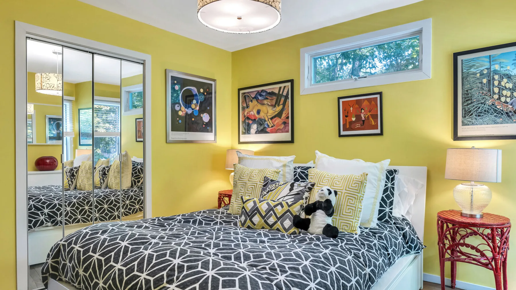 Un dormitorio con una cama de estampado geométrico y cuadros coloridos en la pared.