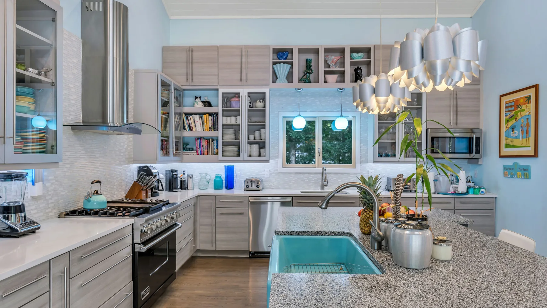Una cocina luminosa con una isla, un fregadero y lámparas colgantes.