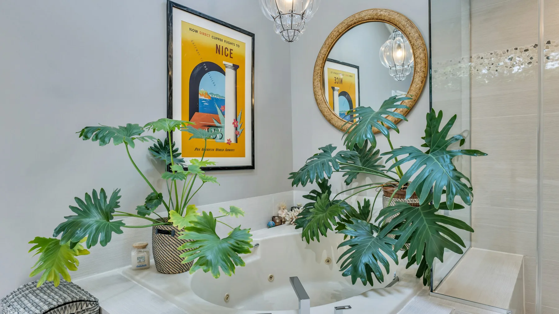 Un baño con un lavabo, plantas frondosas y un póster enmarcado.
