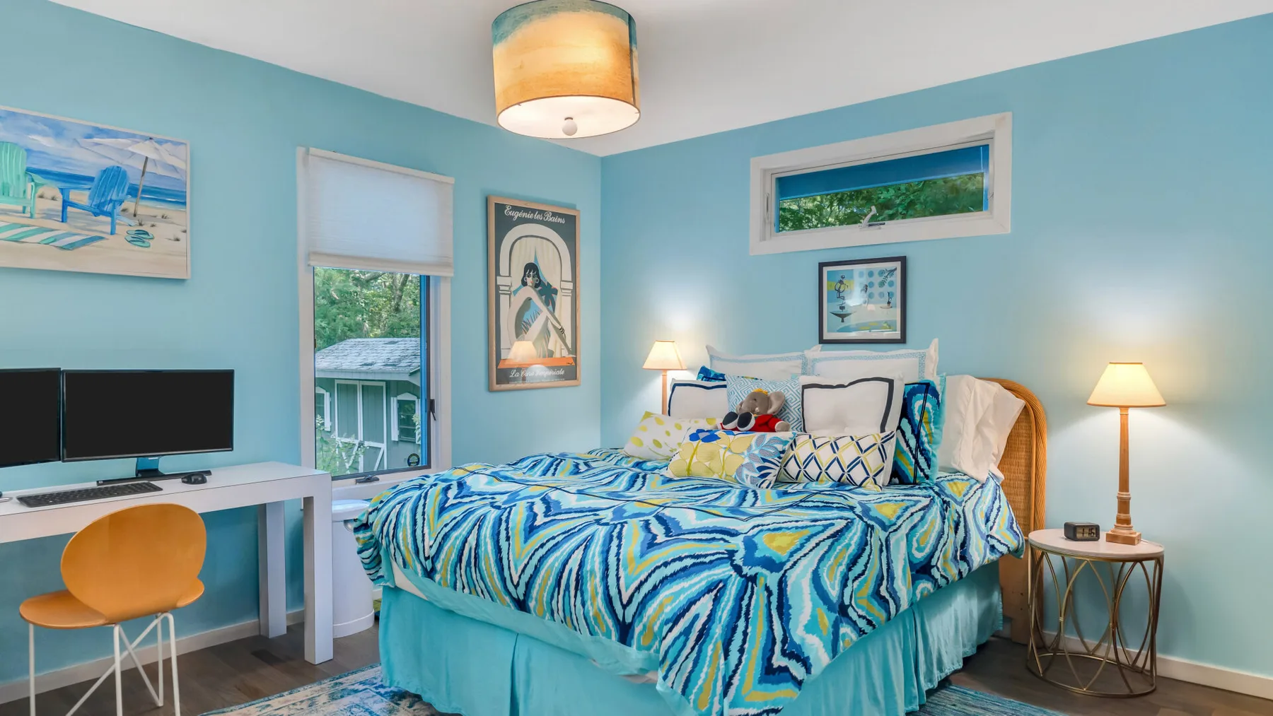 Un dormitorio luminoso con una cama cubierta de ropa de cama azul estampada.