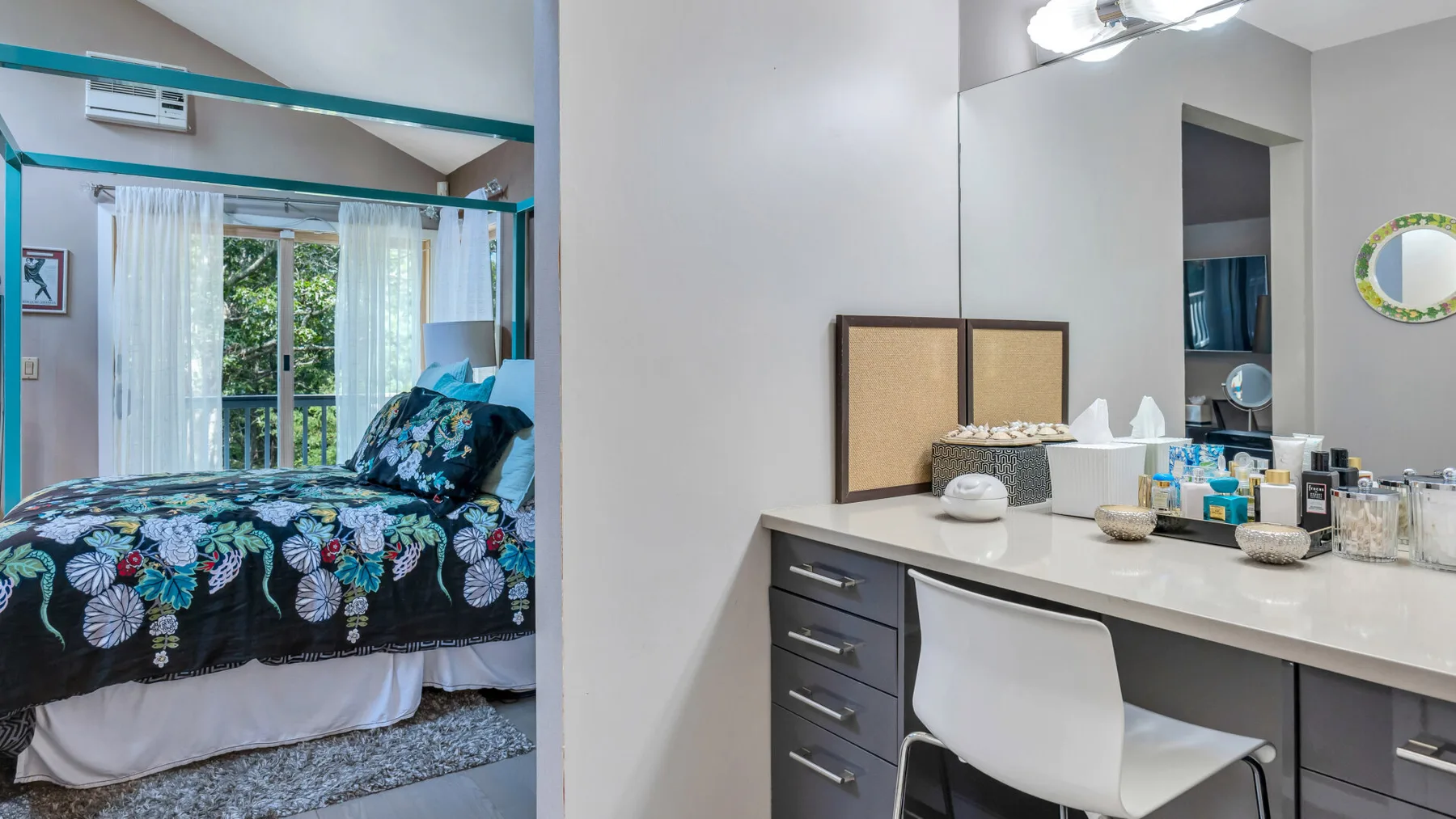 Un dormitorio con una colcha estampada está junto a un tocador y una silla.