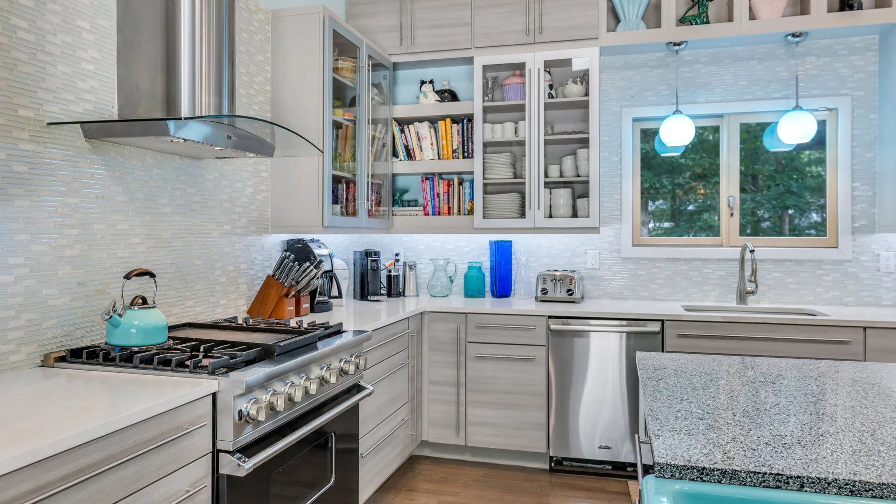 Una cocina luminosa con estufa de gas, electrodomésticos de acero inoxidable y gabinetes de pared.