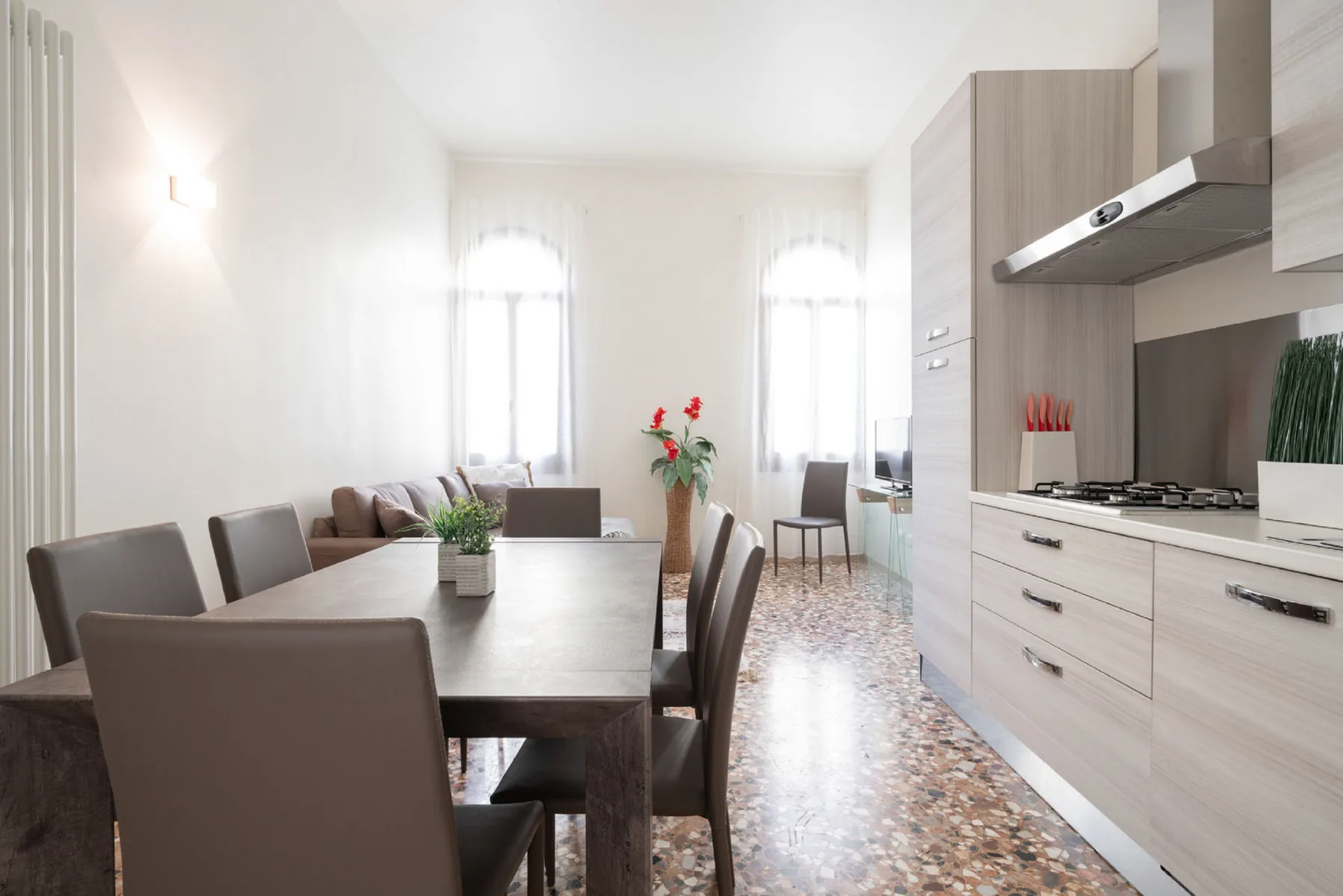 A bright dining area with a table and chairs beside a kitchen.