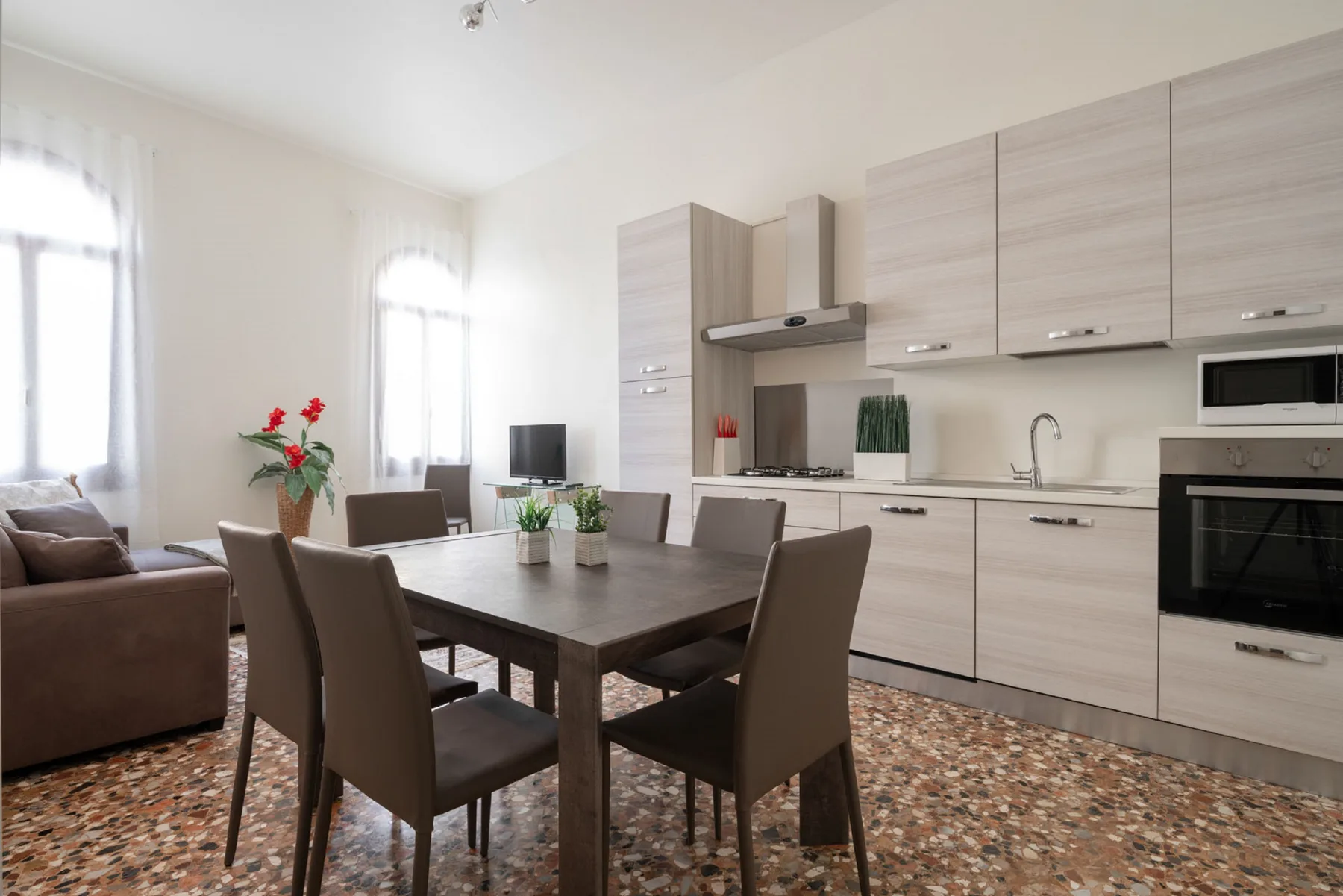A bright open-plan kitchen and dining area has a table, seating, and a living area.
