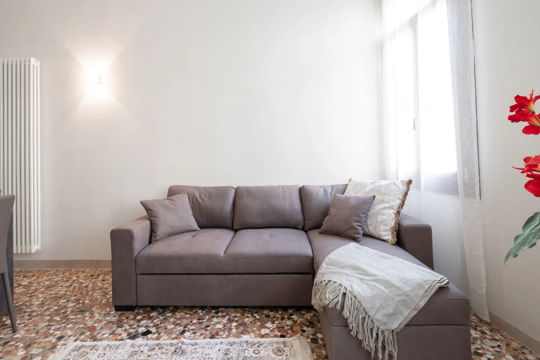 A bright living room with a gray sectional sofa beside a large window.