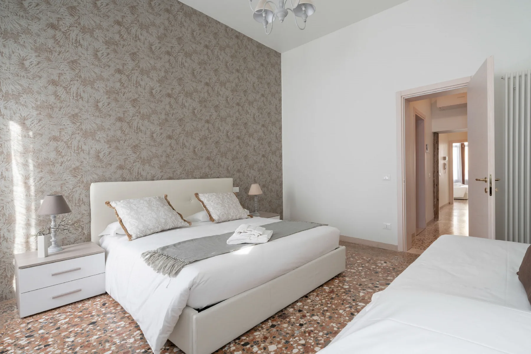 A bedroom with a large bed, a second bed, and an open doorway.