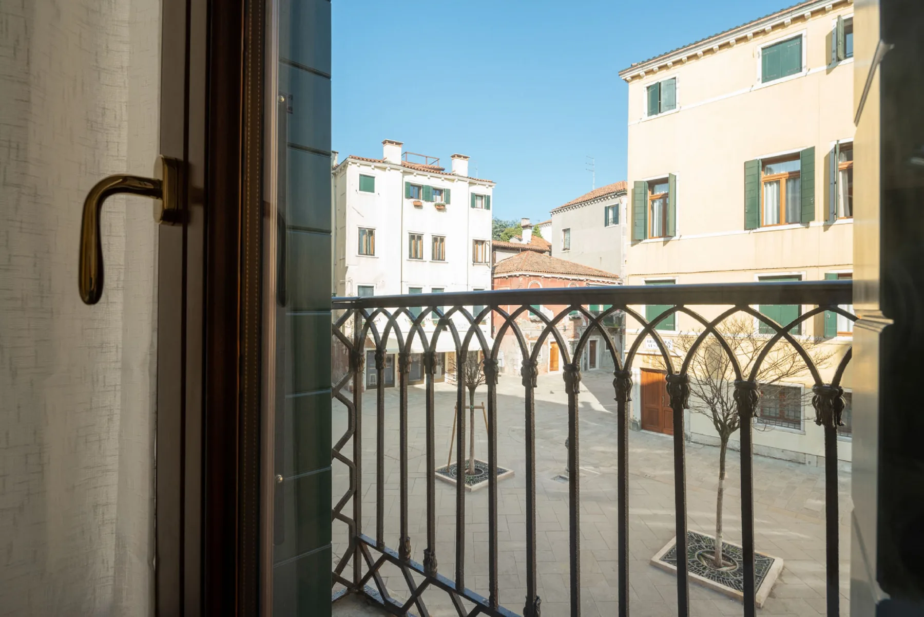 A balcony overlooks a paved courtyard surrounded by light-colored buildings.