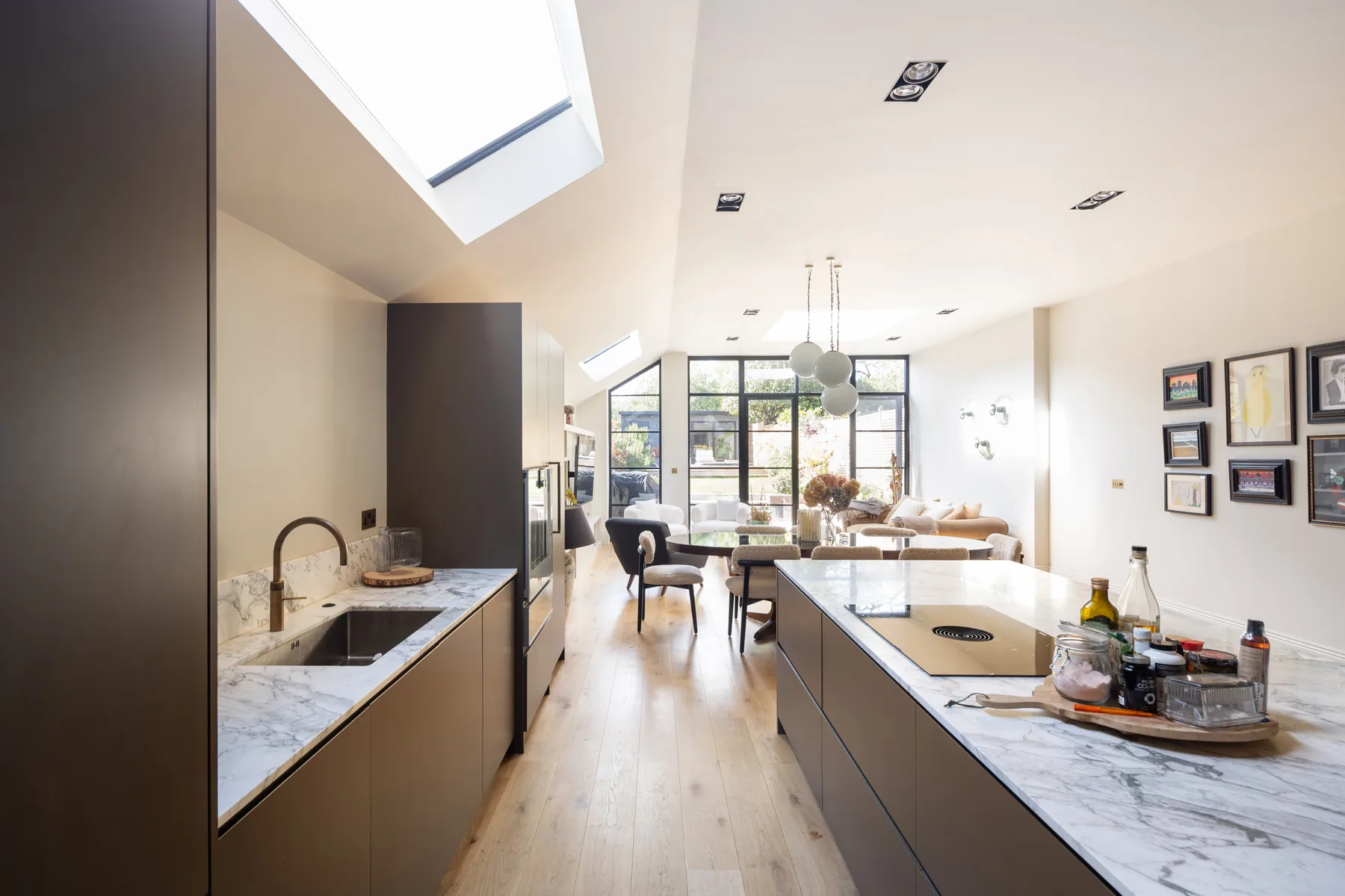 Una luminosa cocina-comedor de planta abierta con una isla larga y grandes ventanas.