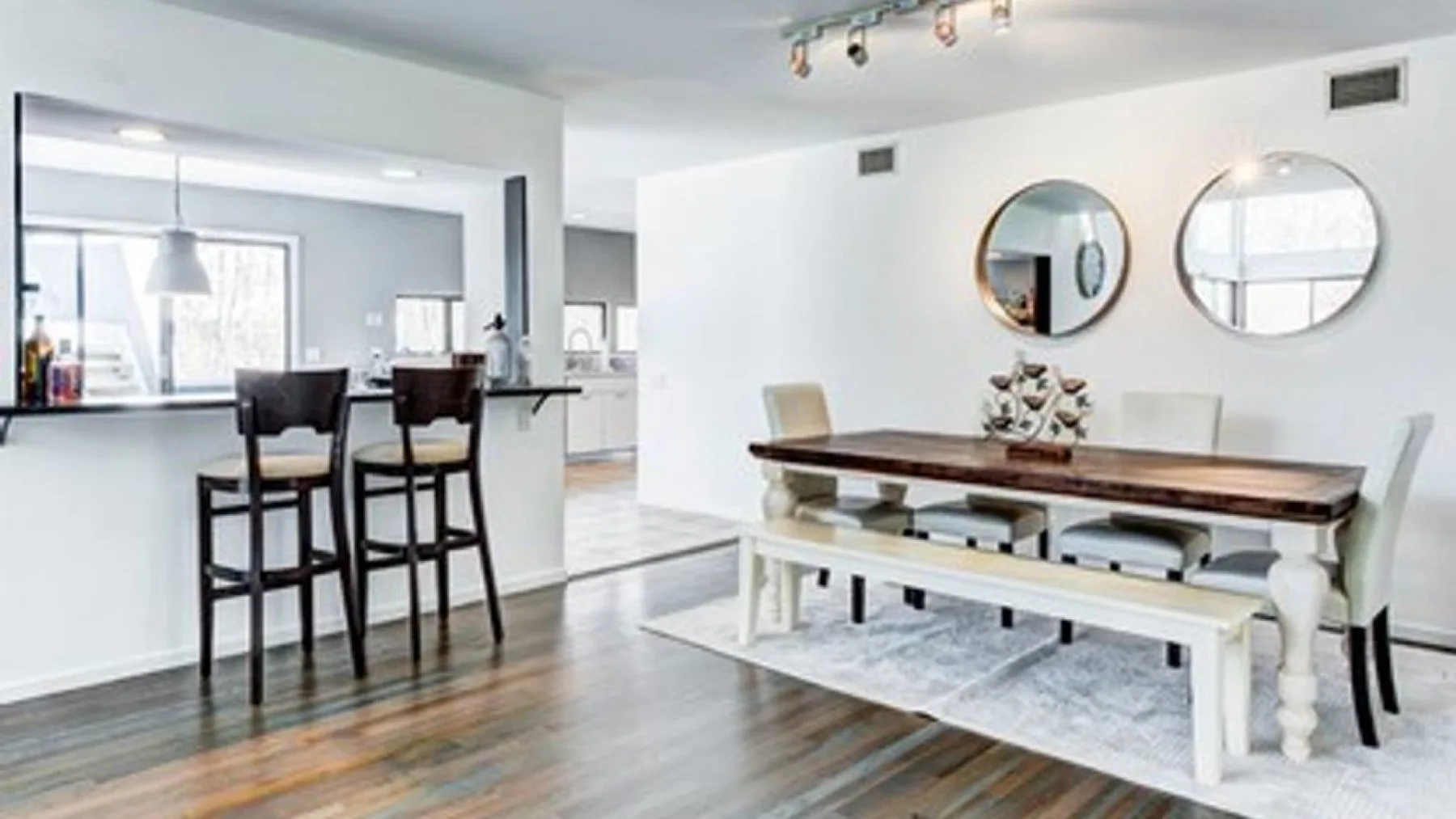 A bright dining area with a long table beside a kitchen counter.