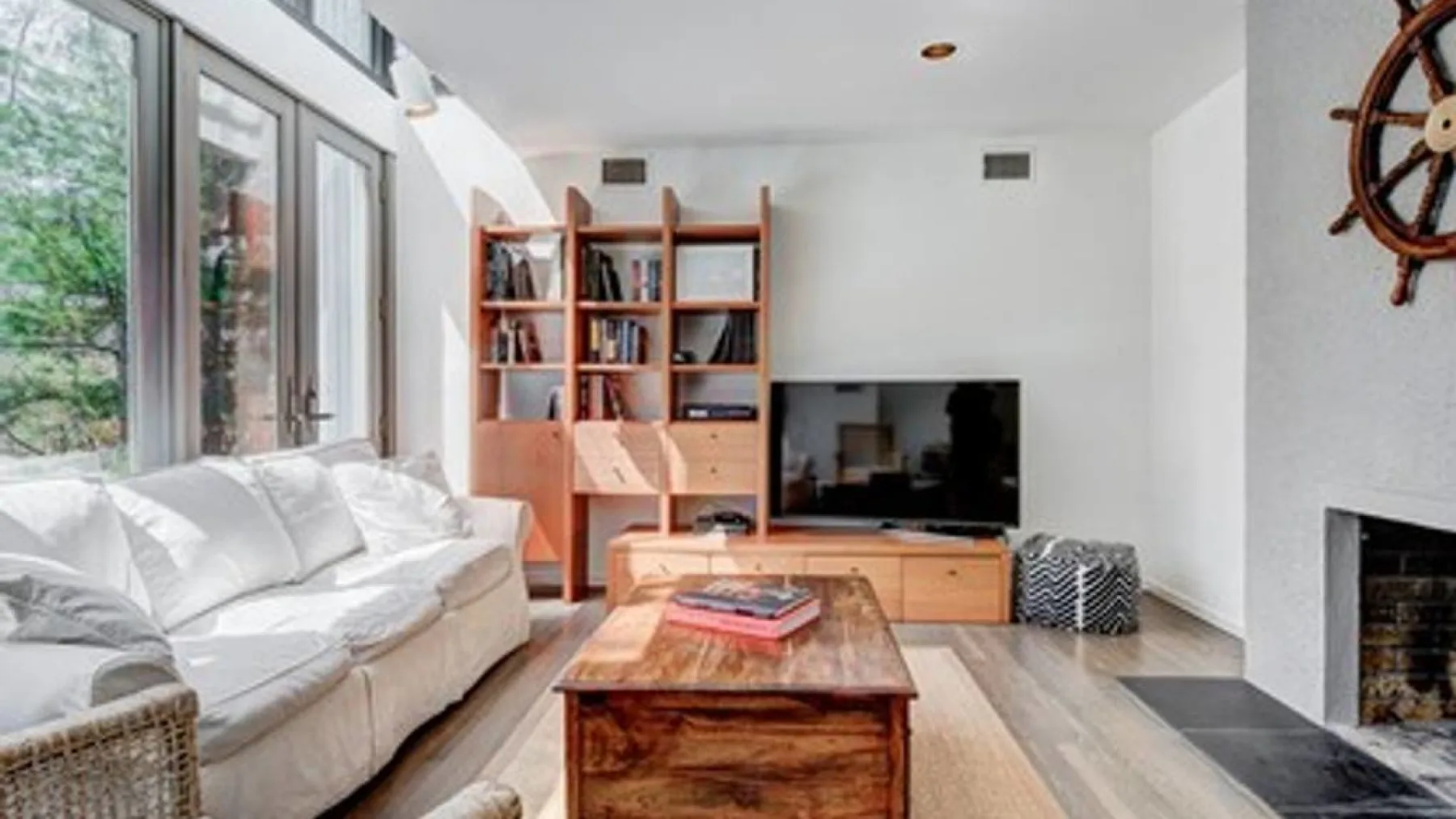 Una sala de estar luminosa con asientos, una mesa de centro de madera y un televisor.