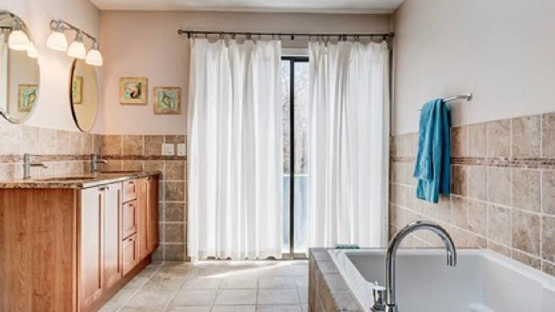 Un baño con bañera, lavabo y una ventana con cortinas.