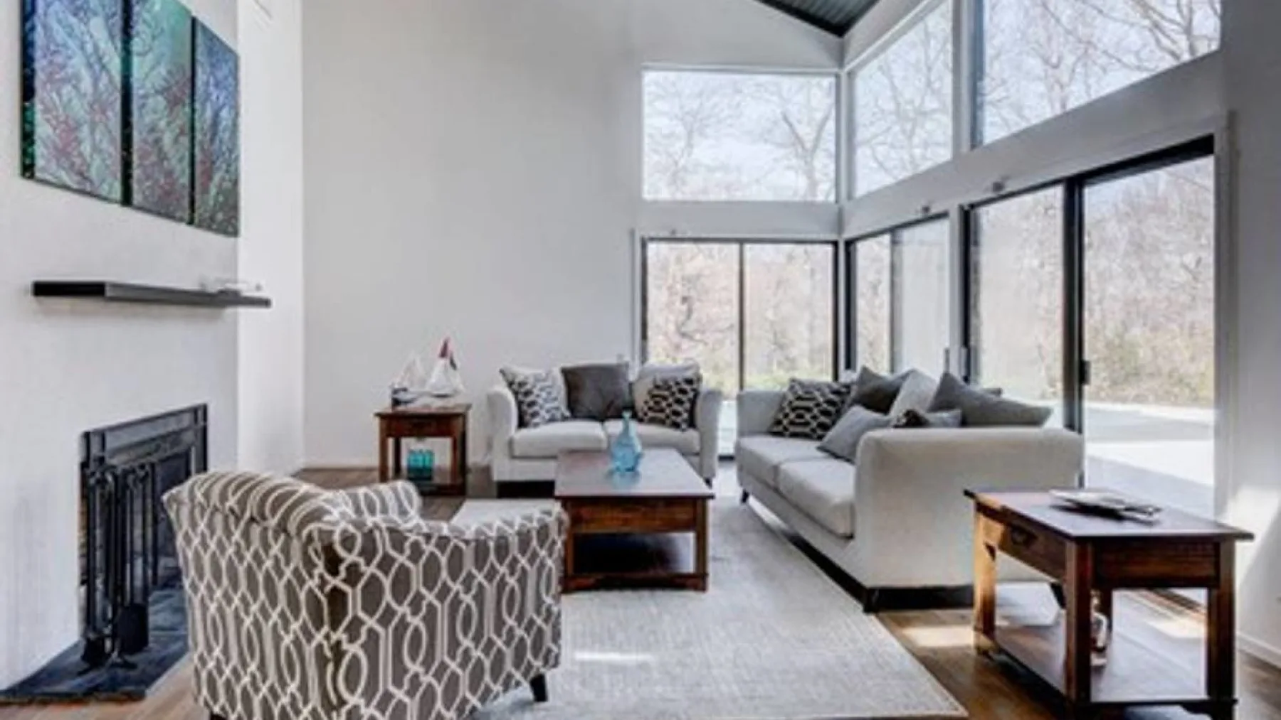 A bright living room with seating arranged around a coffee table beside large windows.
