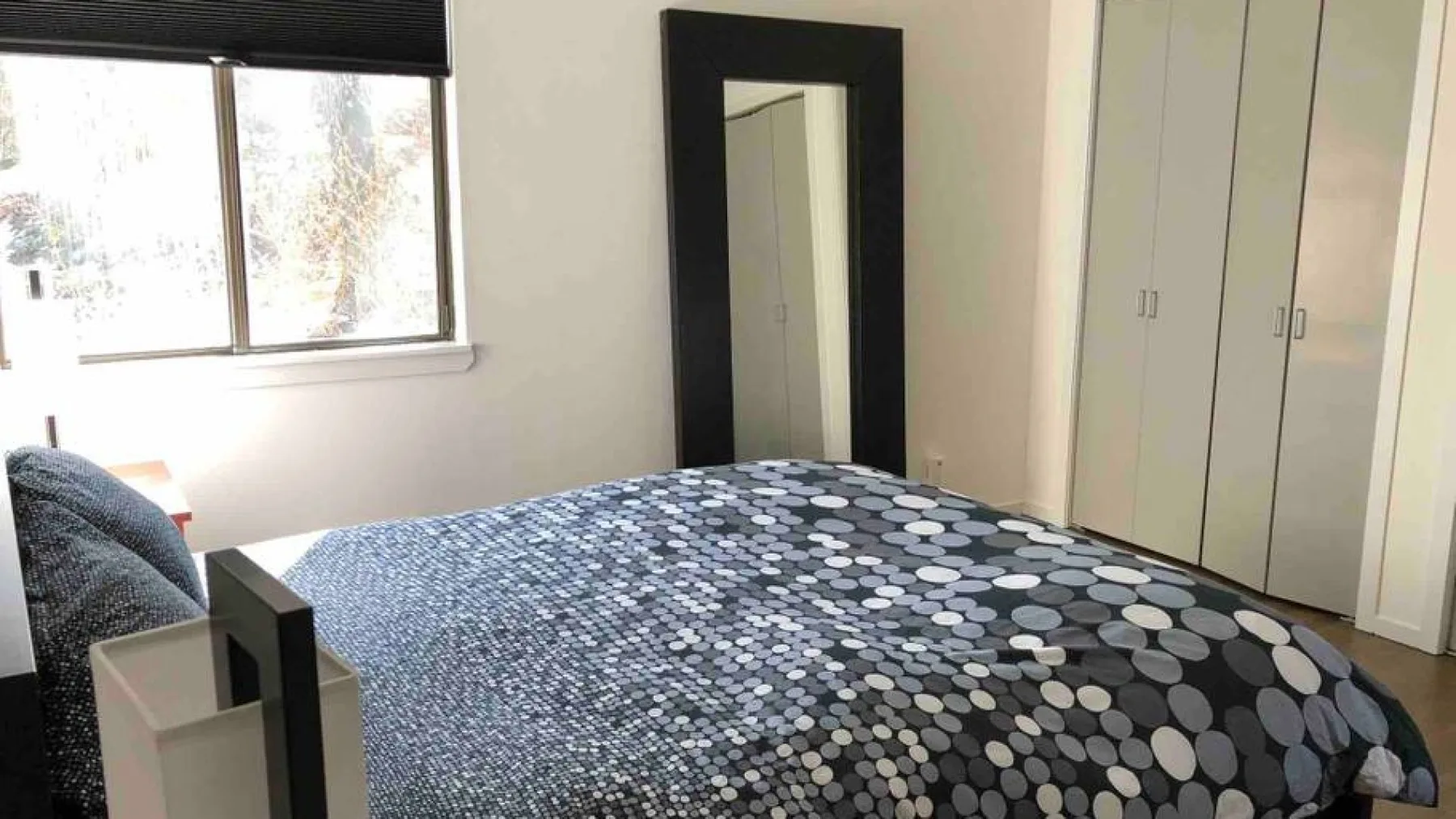 Un dormitorio con una cama cubierta con ropa de cama estampada junto a una ventana.
