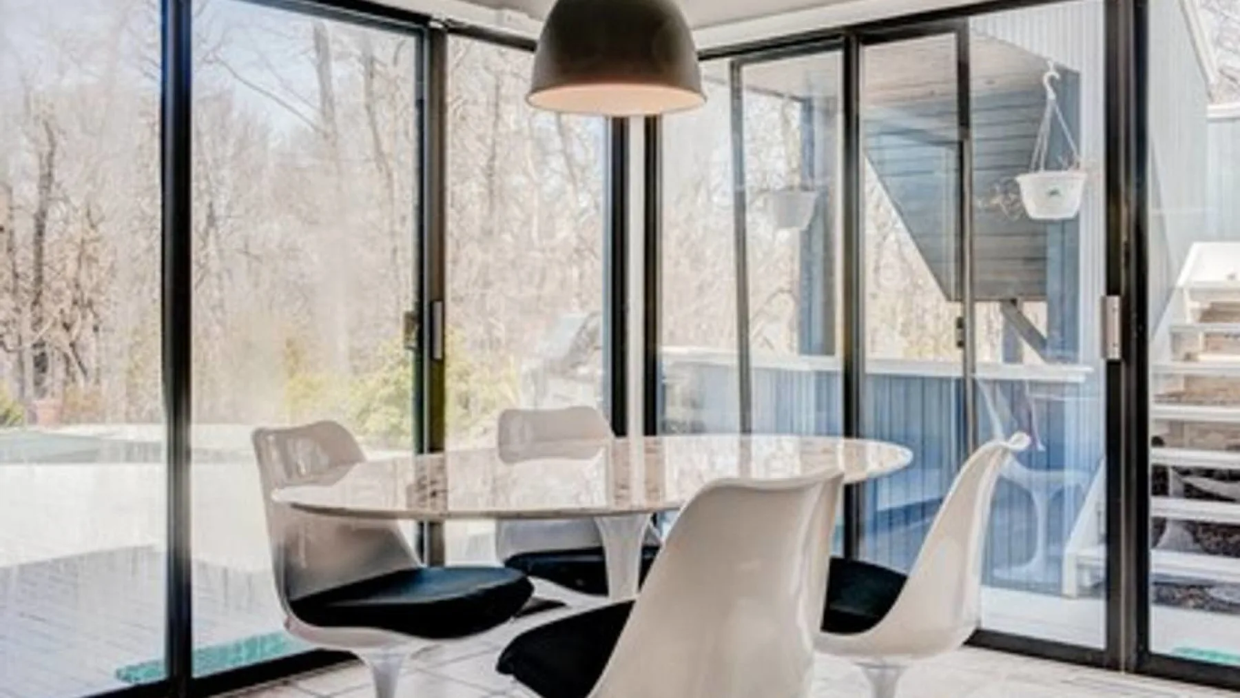 Un comedor con una mesa y asientos junto a grandes ventanas.