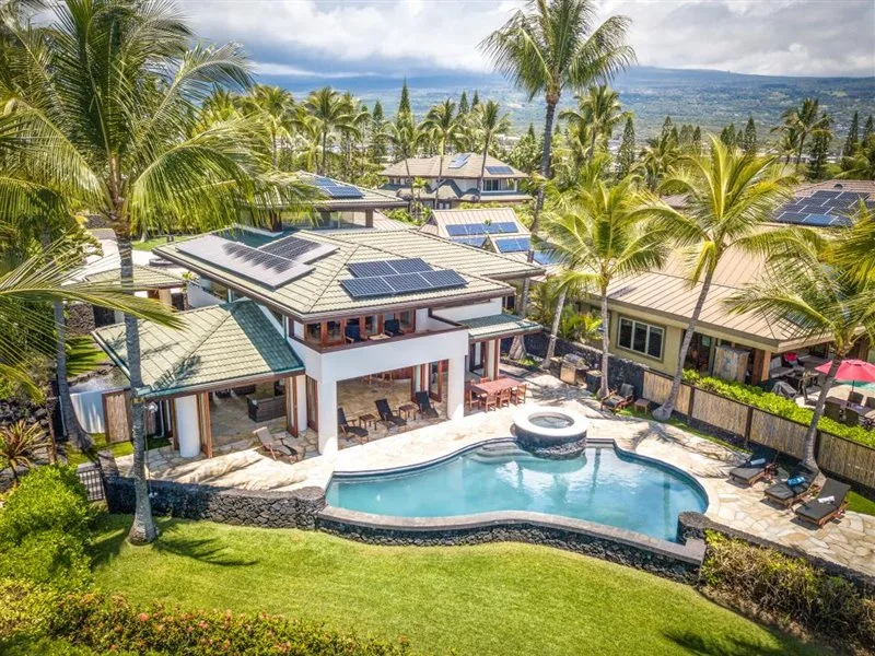 Vista aérea de una propiedad tropical con piscina y paneles solares.