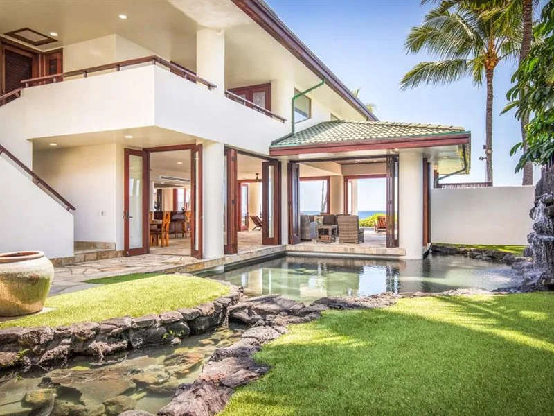 Una casa moderna se abre a una pequeña piscina y un césped verde.