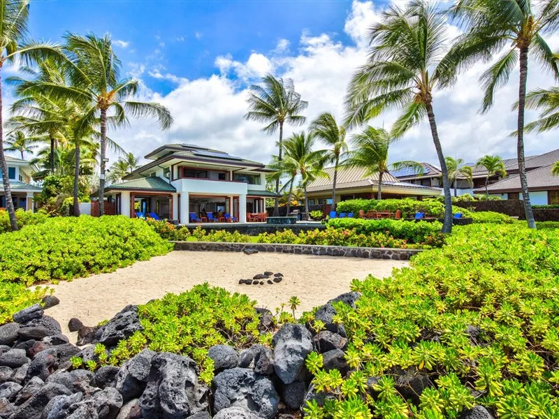 Un edificio de resort tropical está rodeado de palmeras y vegetación.