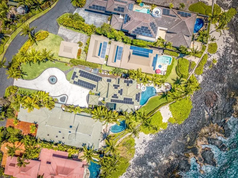 Una vista aérea muestra una propiedad costera con piscinas, jardines y una costa rocosa.