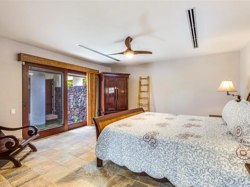 Un dormitorio con una cama grande, un ventilador de techo y puertas corredizas de vidrio.