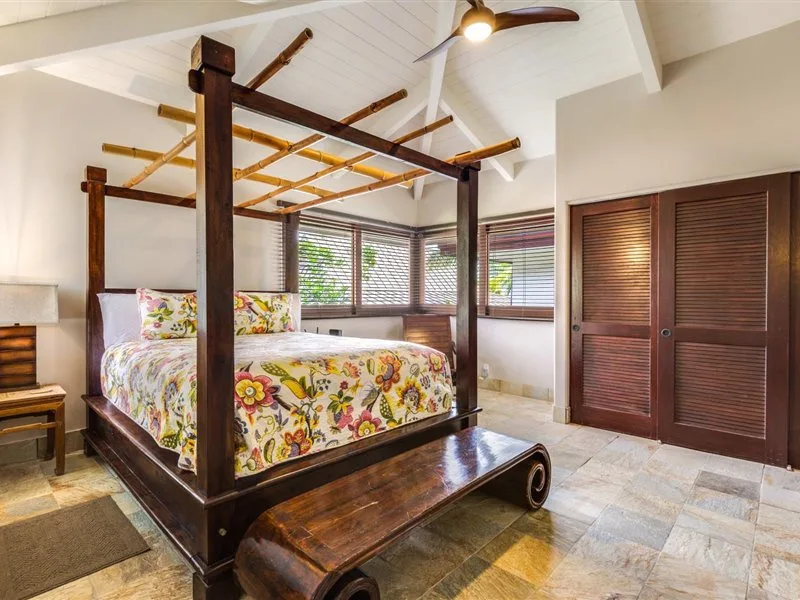 Un dormitorio con una cama con dosel de madera oscura y ropa de cama floral.