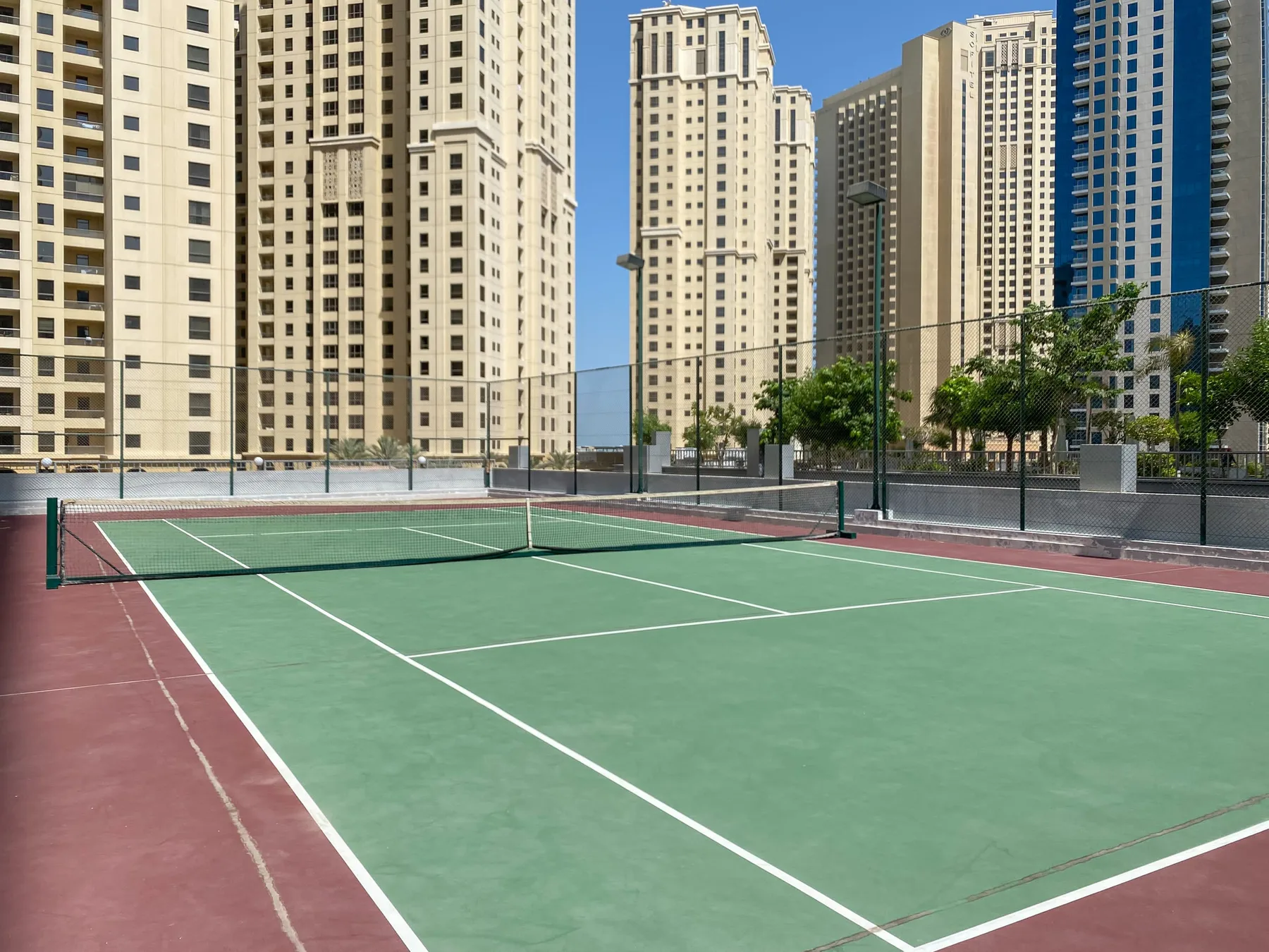 Una pista de tenis al aire libre con edificios altos al fondo.