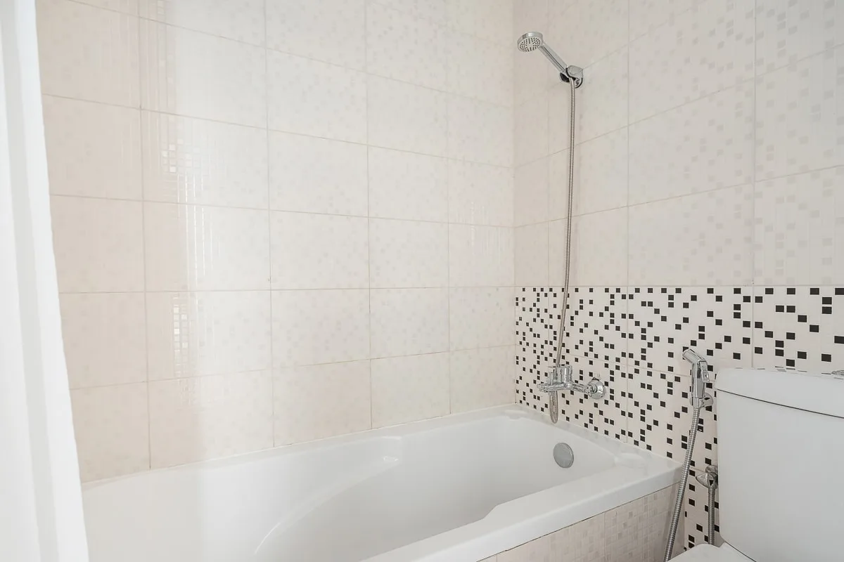 Un baño con azulejos, bañera y ducha montada en la pared.