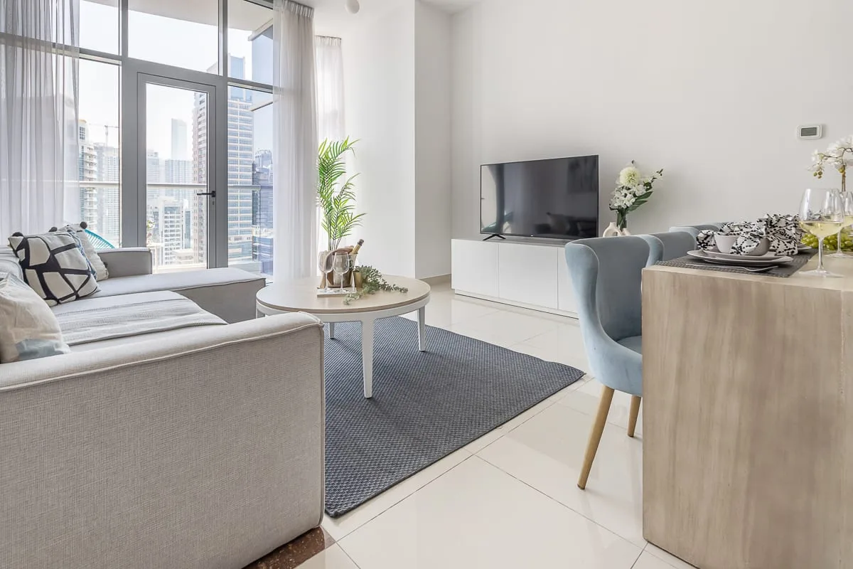 Una luminosa sala de estar y comedor con ventanas amplias y un televisor.