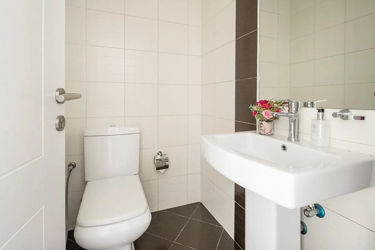 Un baño alicatado con un inodoro y un lavabo blanco.