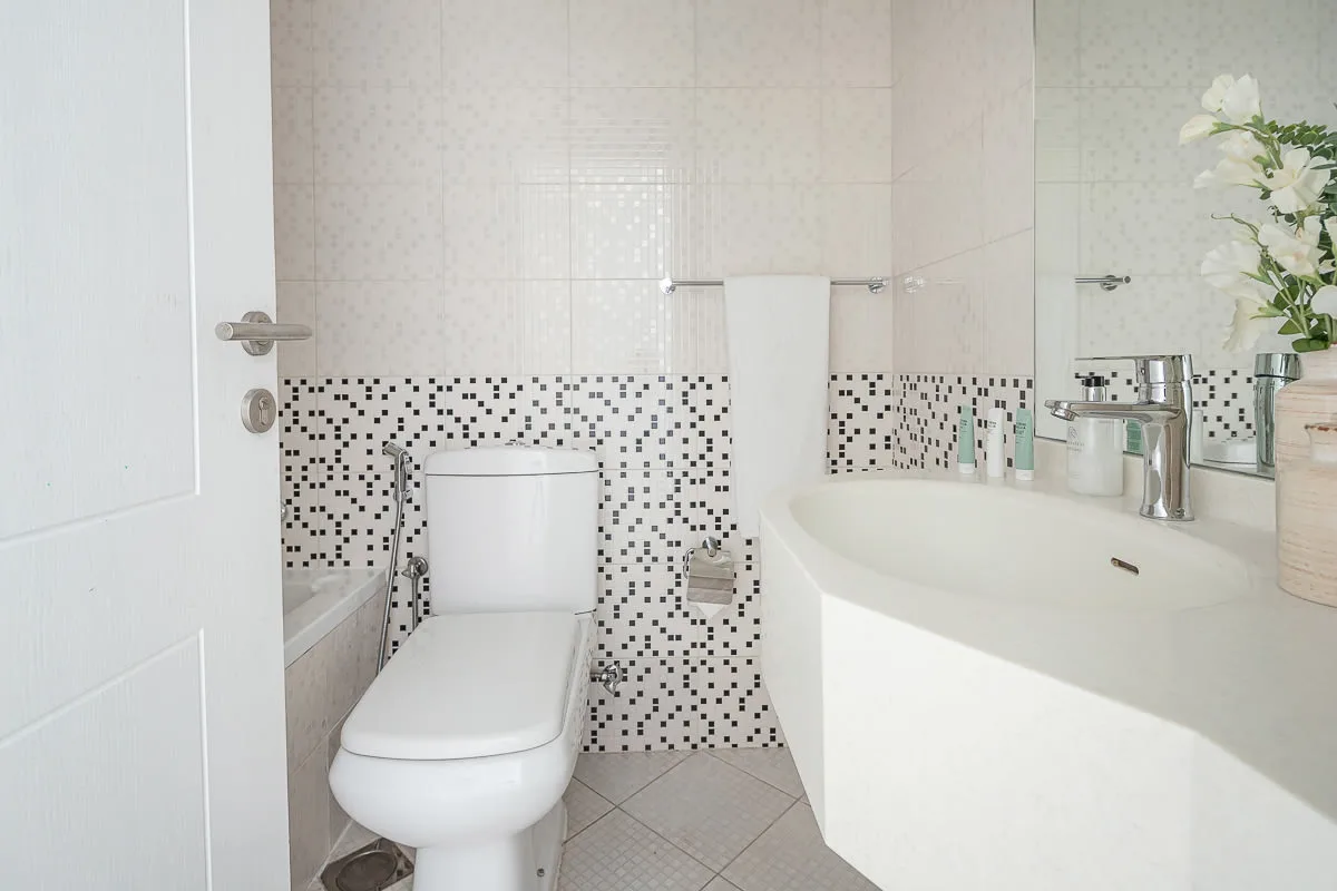 Un baño con inodoro, lavabo curvo y azulejos estampados.