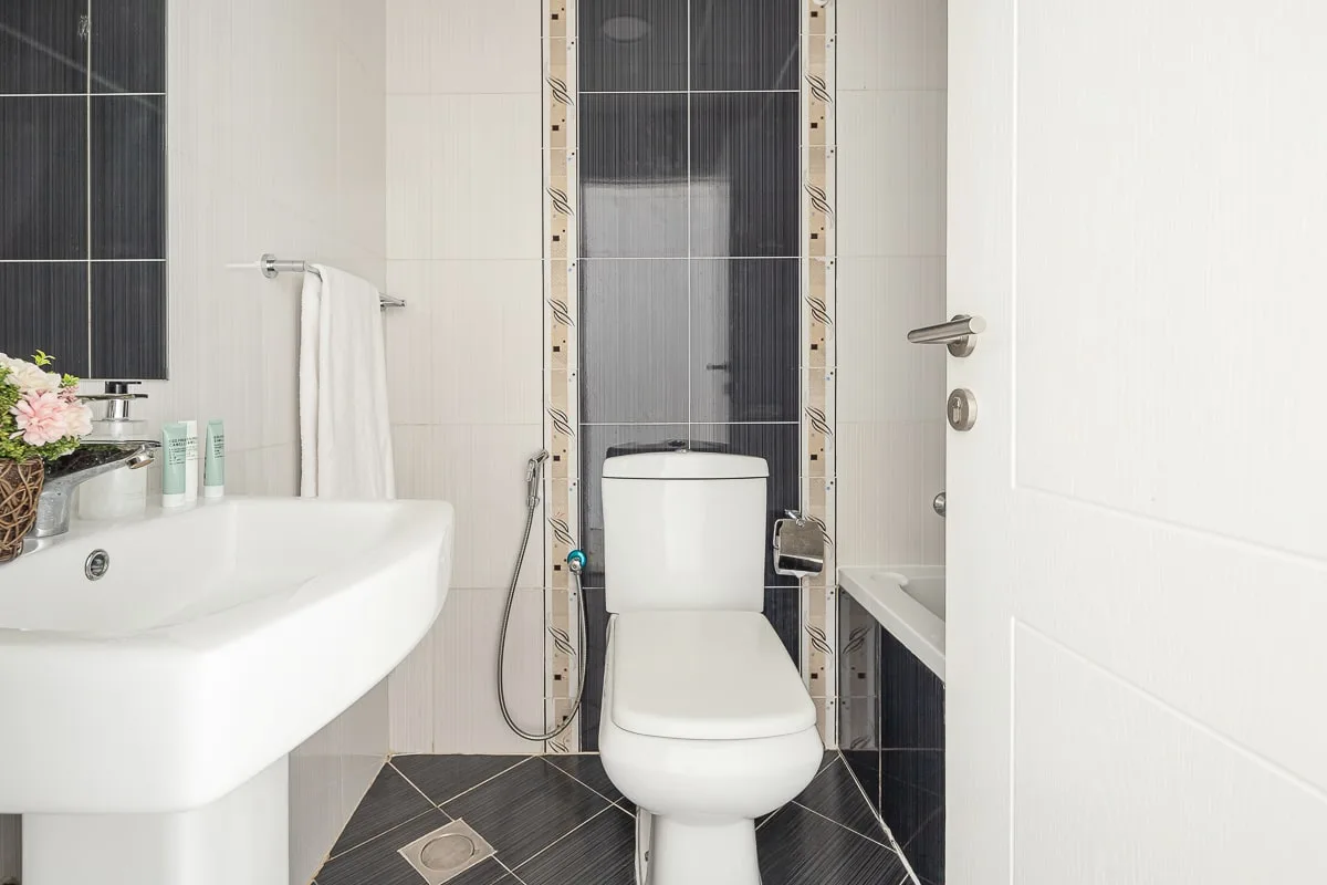 Un baño luminoso con lavabo, inodoro y paredes de azulejos.