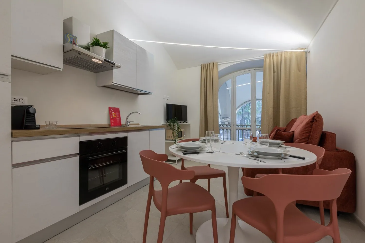 A dining area with a round table beside a compact kitchen.