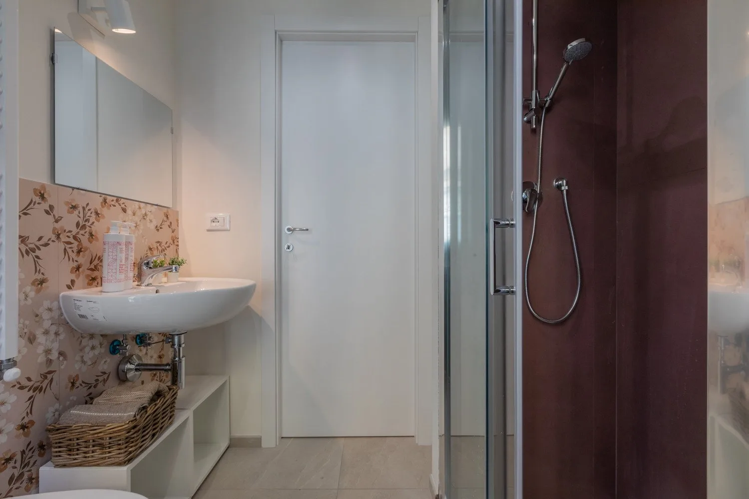 A bathroom with a wall-mounted sink and a glass-enclosed shower.