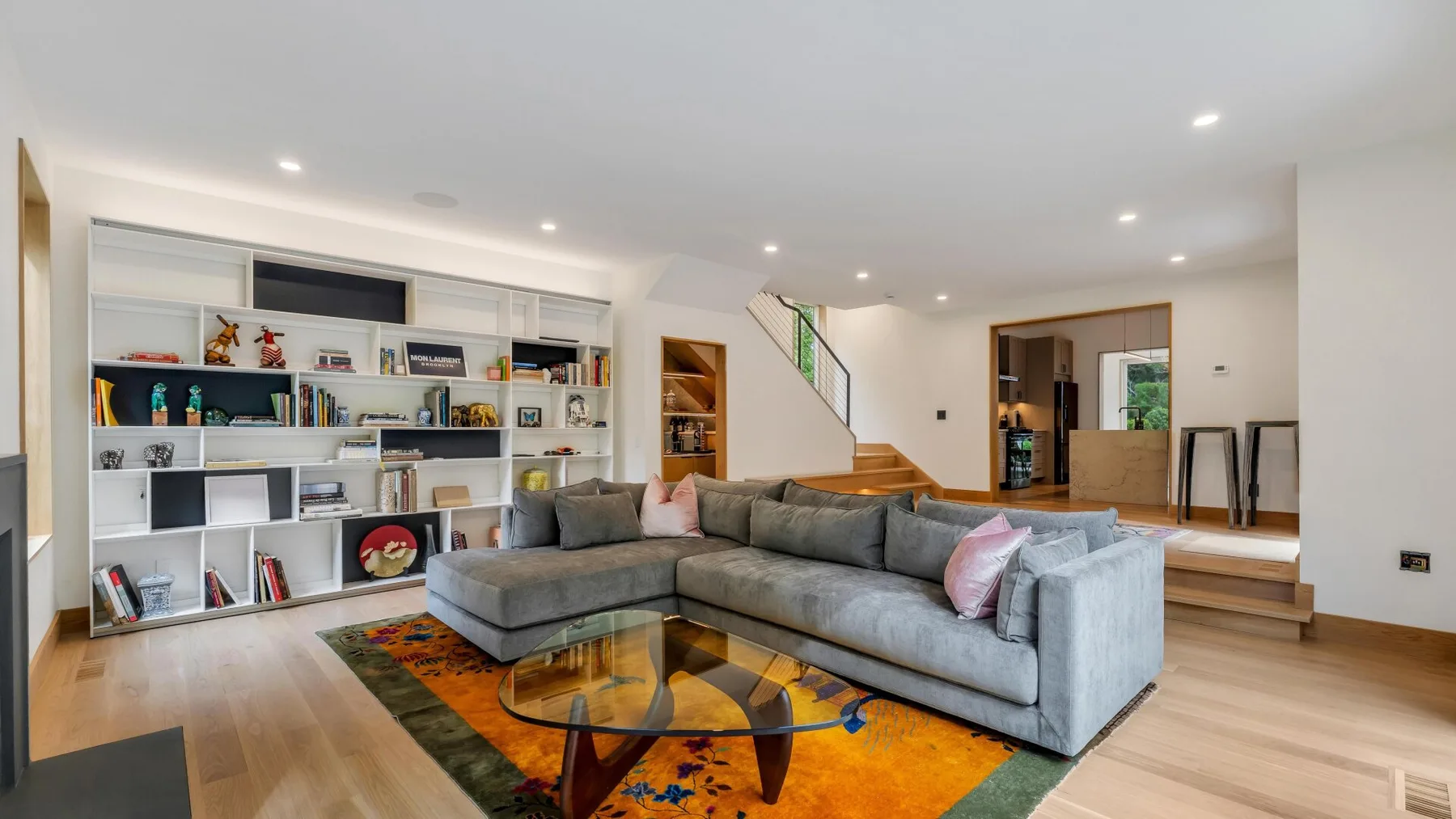 A living room with a gray sectional and colorful rug.