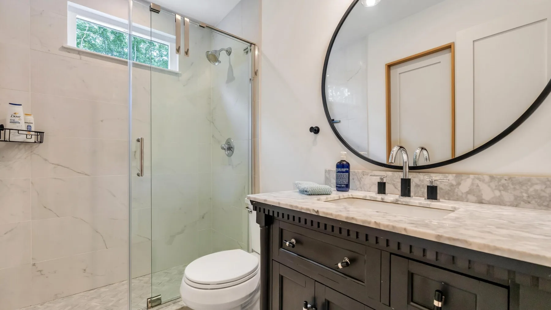 A bathroom with a glass shower, toilet, and wide vanity.