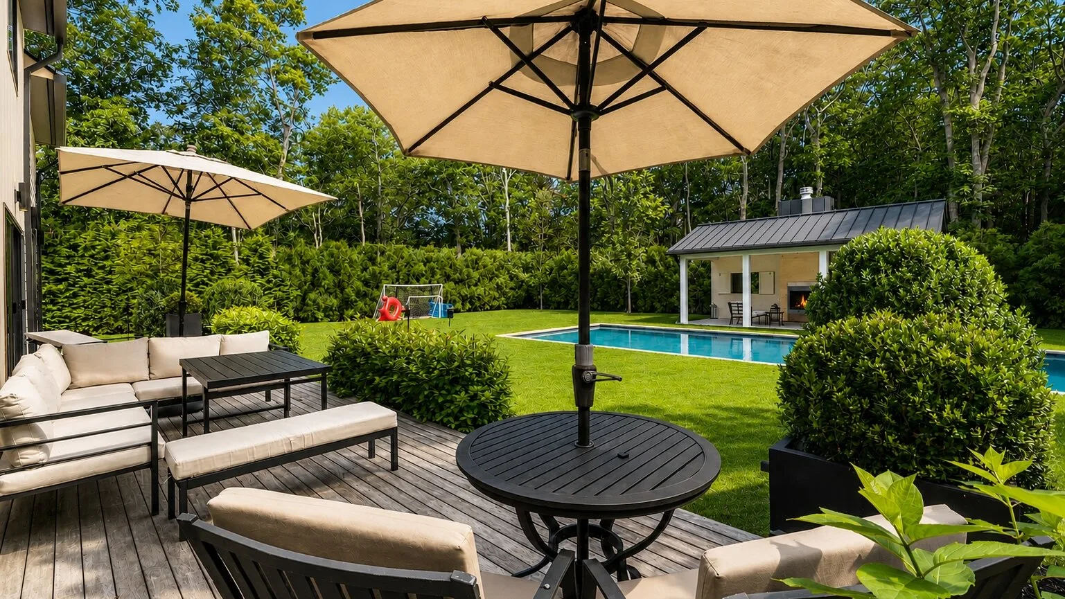 Un patio trasero con asientos al aire libre da a una piscina y un césped.