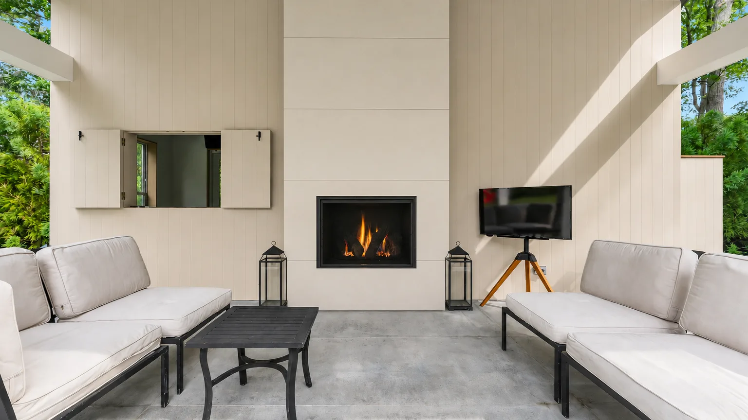 A bright living room with white seating, a dark coffee table, and a fireplace.