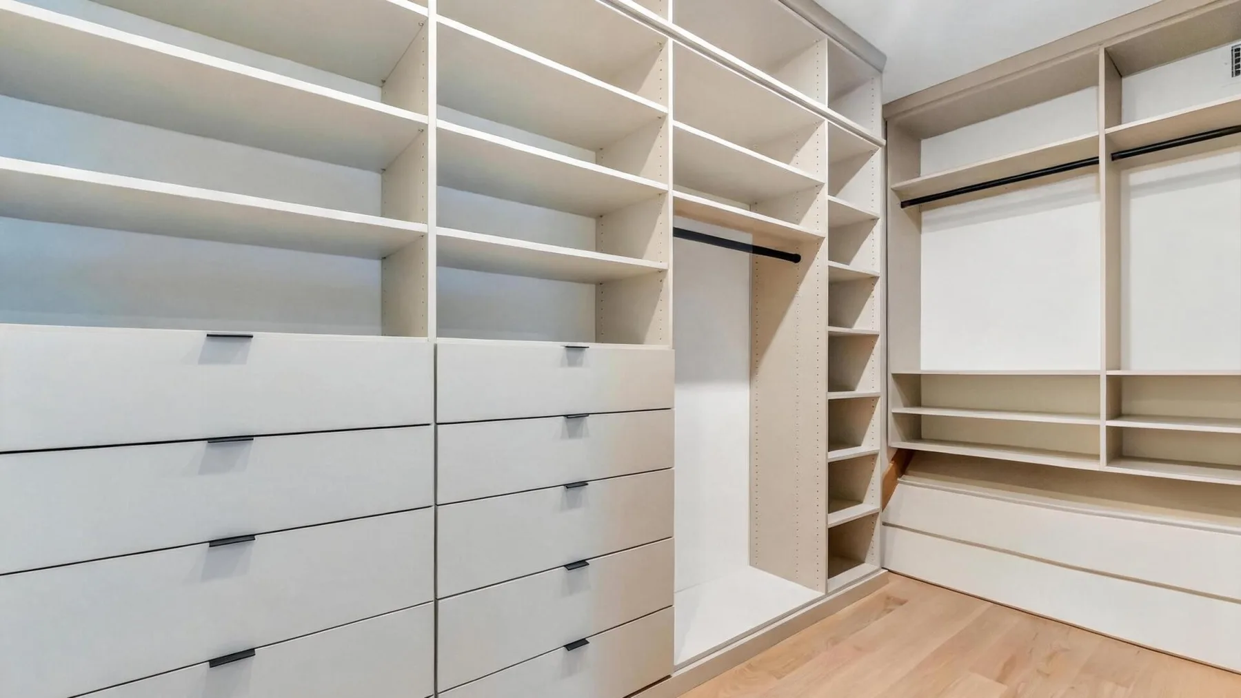 A walk-in closet with built-in shelving, drawers, and hanging rails.