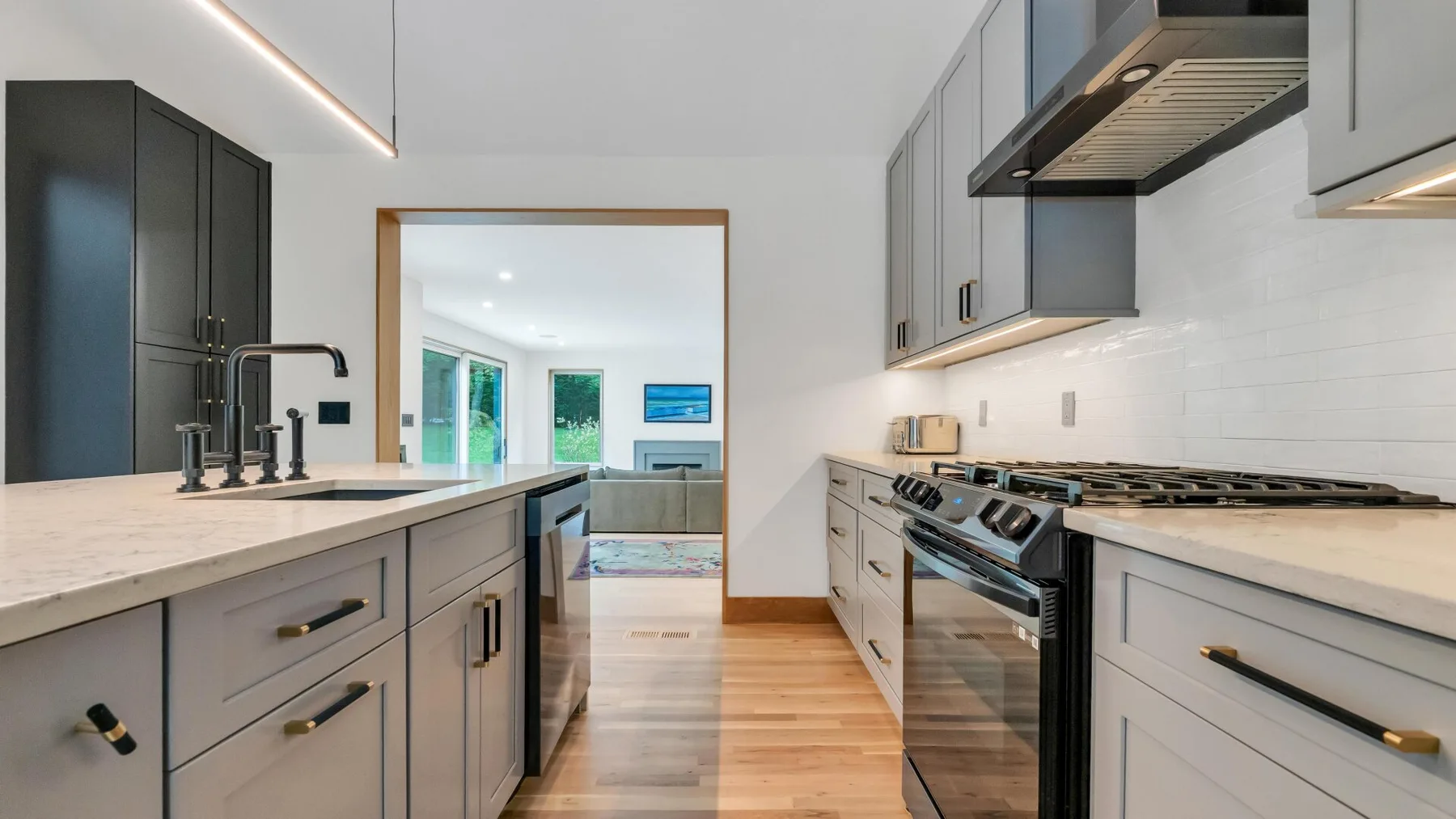 A modern kitchen with gray cabinetry, light countertops, and a stainless-steel range.