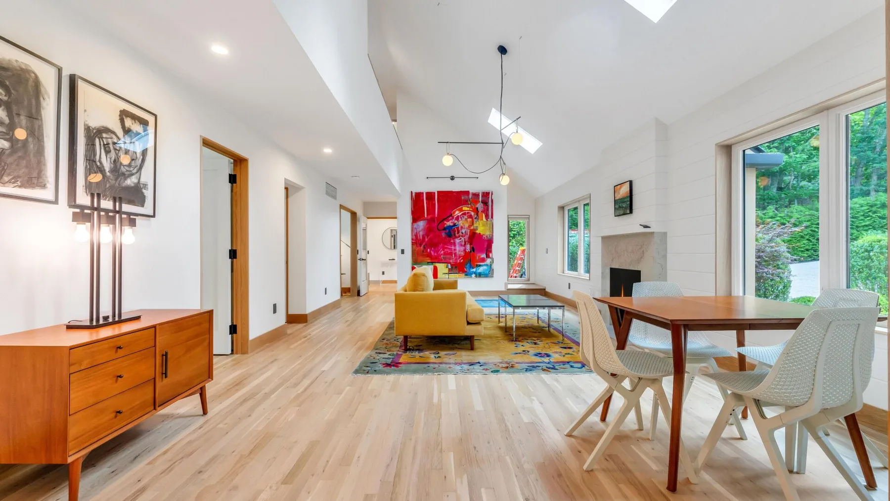 A bright living and dining area features a dining table beside large windows.