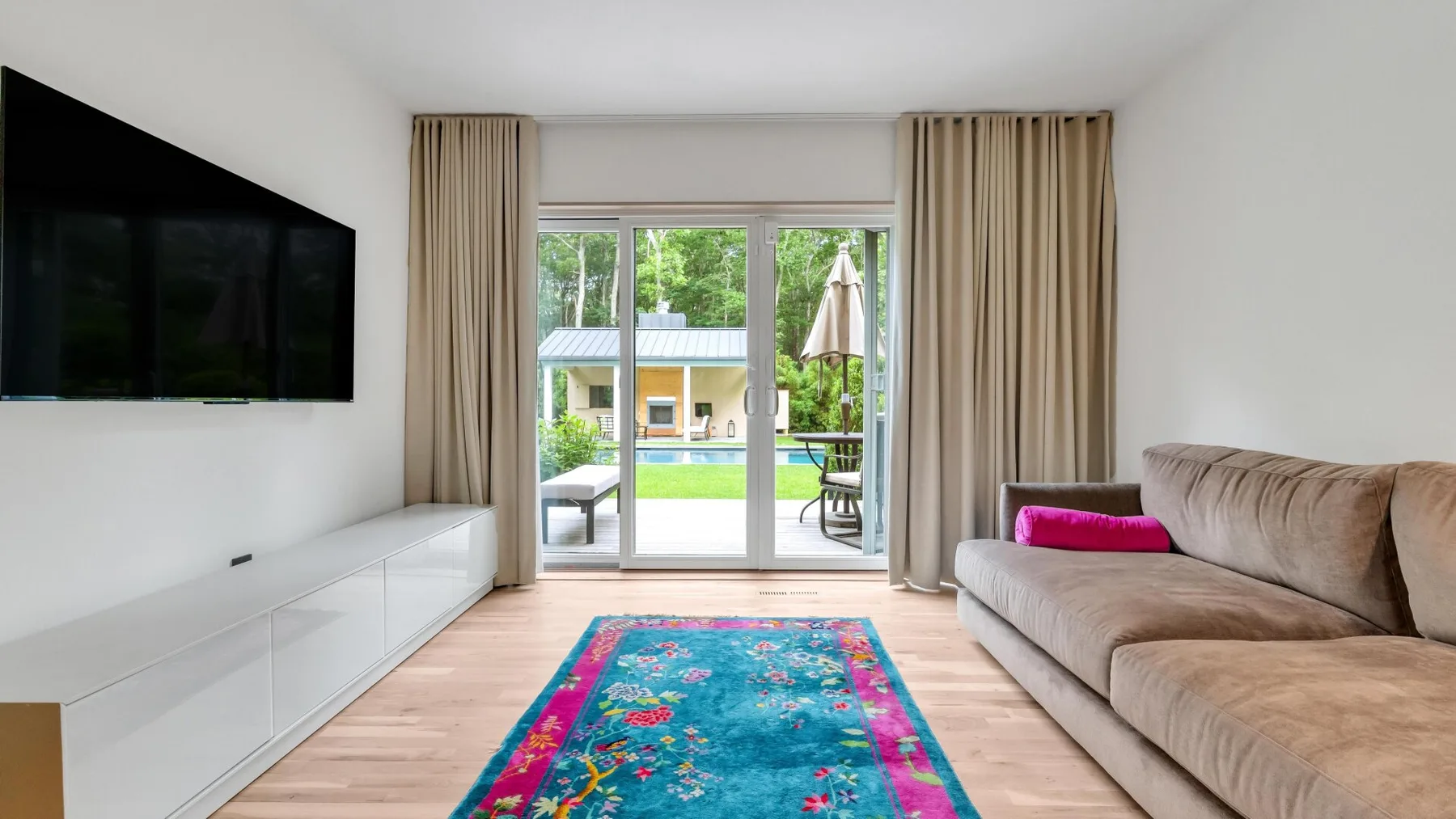 A living room with a television, seating, and glass doors opening to a patio.
