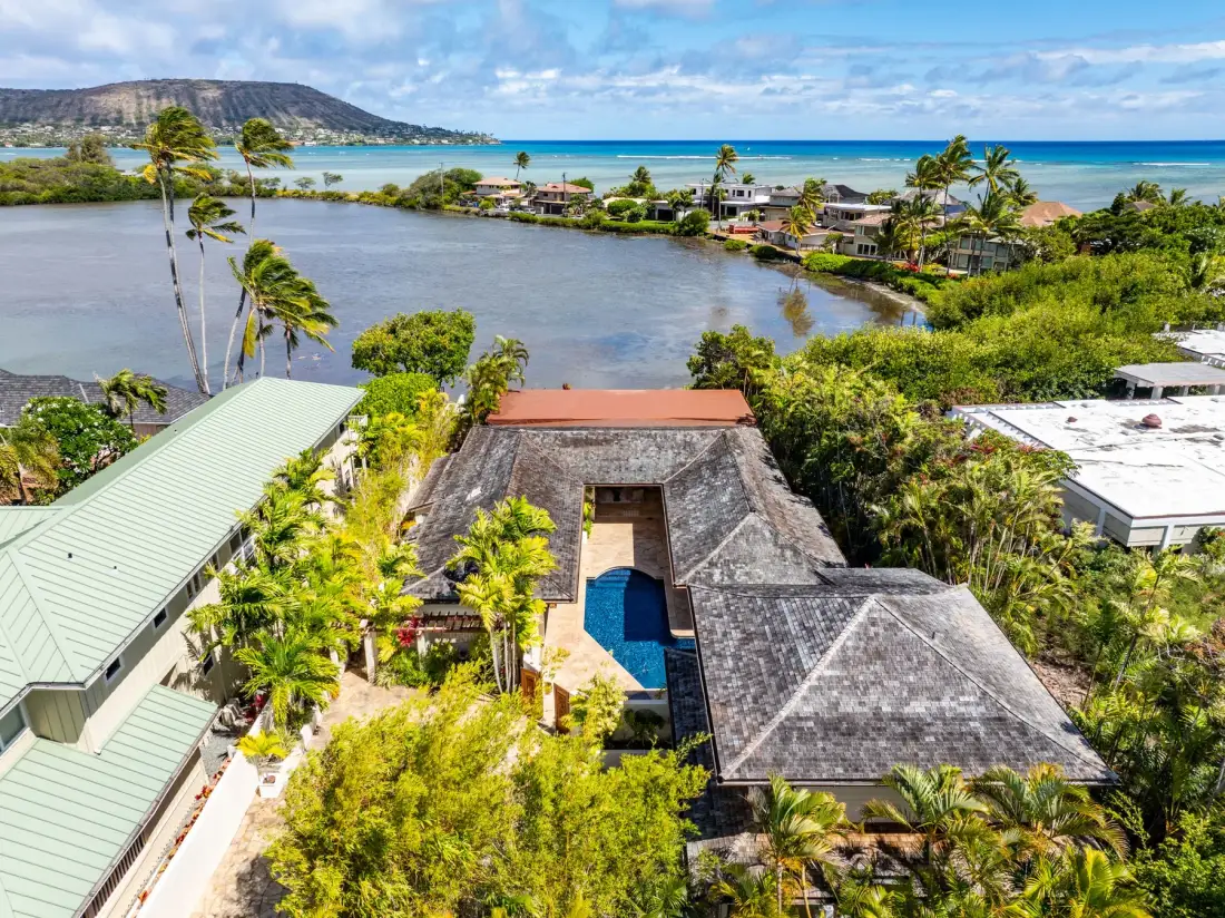 An aerial view of buildings and a swimming pool beside a tropical lagoon.