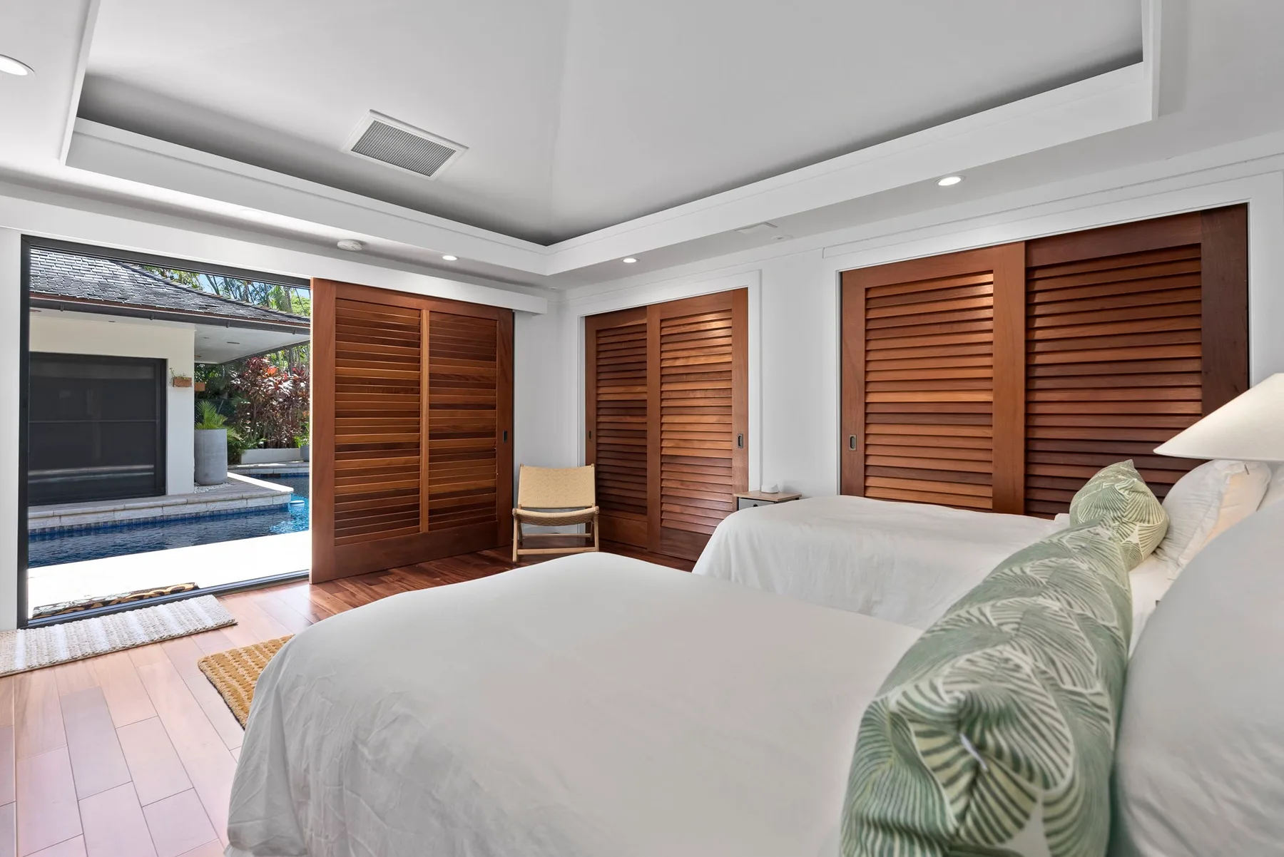 Un dormitorio con una cama y puertas de lamas de madera que dan a una piscina exterior.