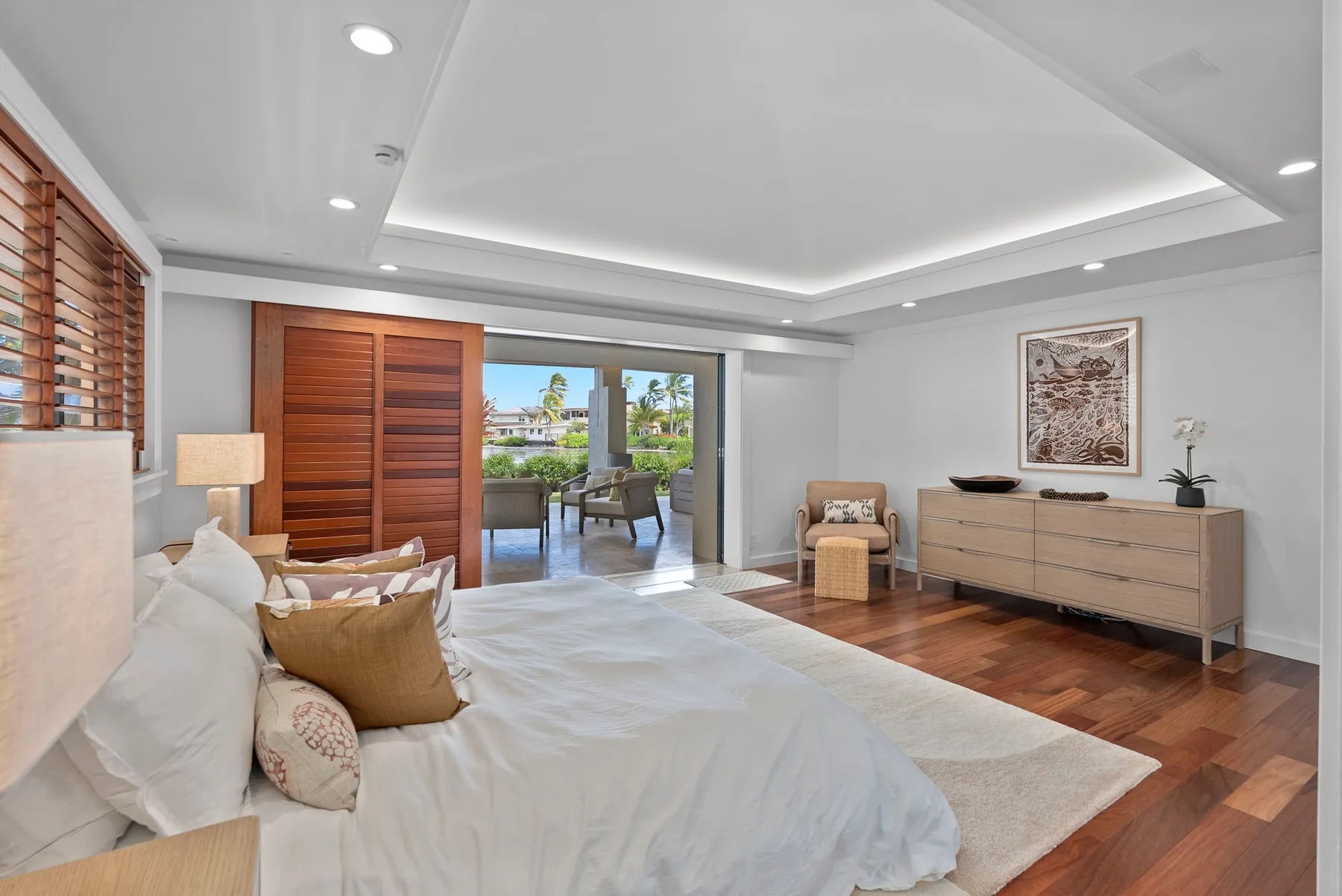 Un dormitorio luminoso con una cama, puertas corredizas de madera y una cómoda.