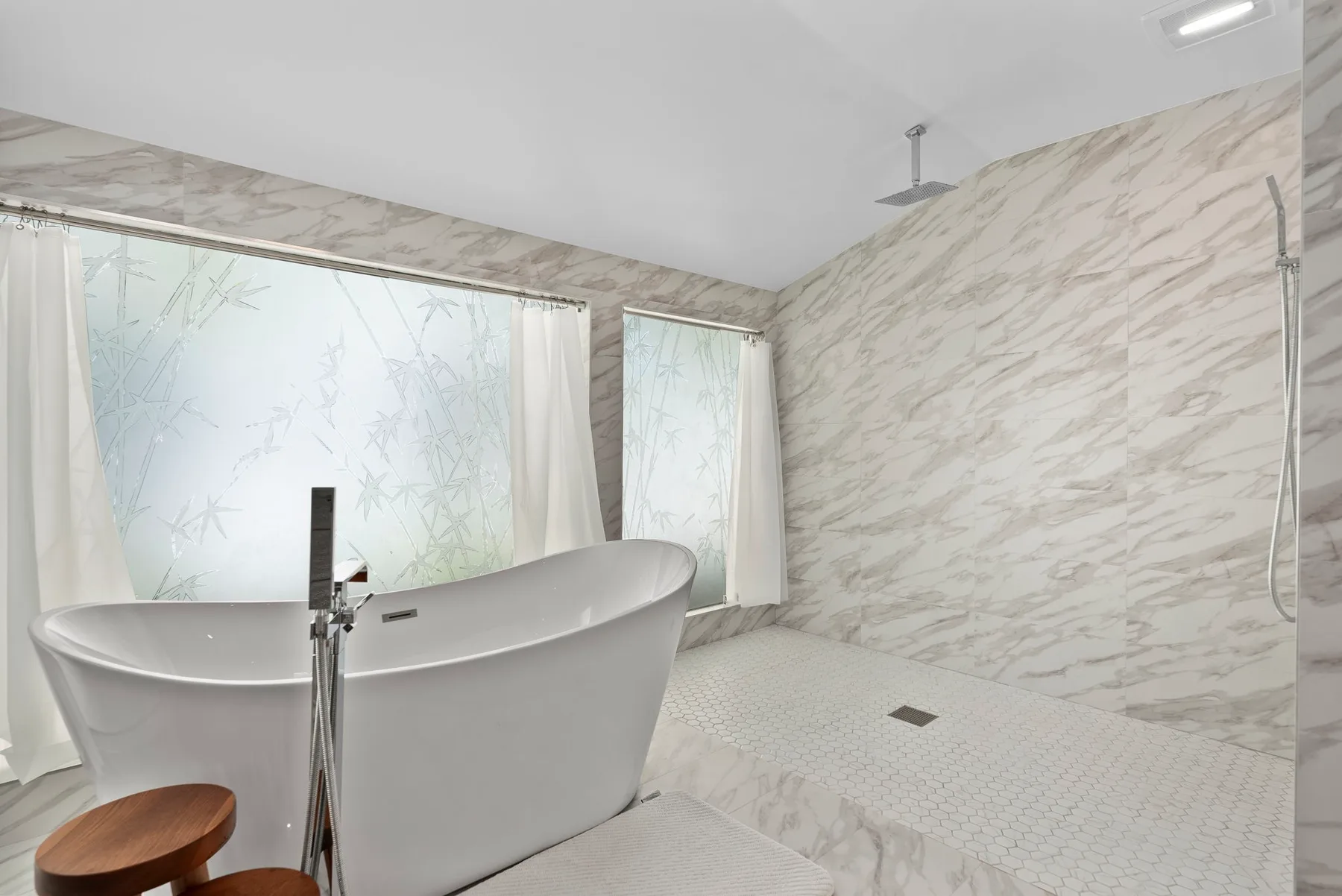 Un baño luminoso con bañera exenta y zona de ducha con azulejos.