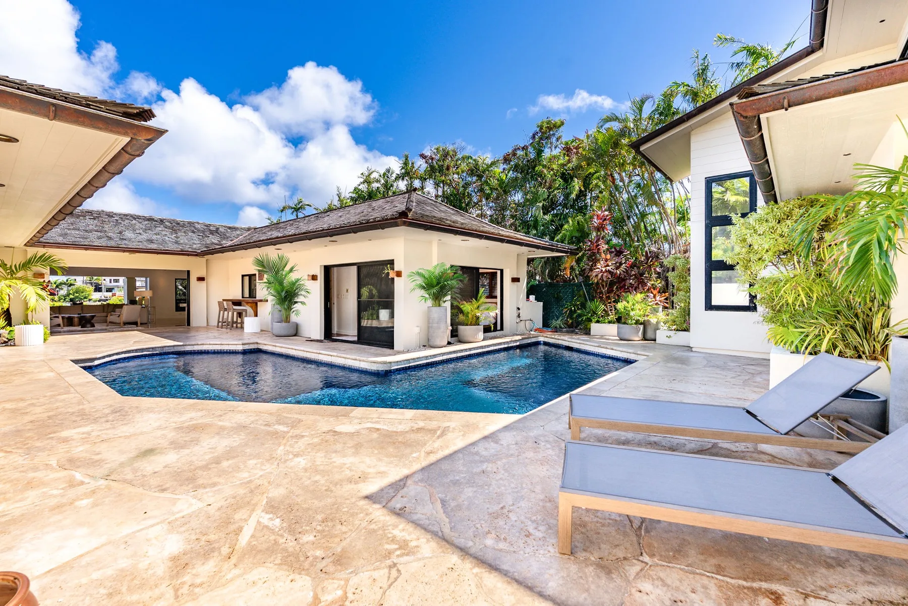 A courtyard pool sits beside a low modern building and lounge seating.
