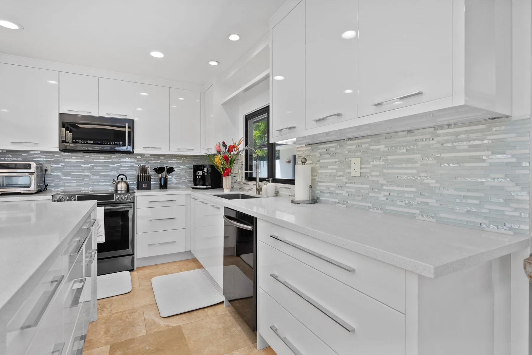 Una cocina luminosa con gabinetes blancos, amplias encimeras y electrodomésticos de acero inoxidable.