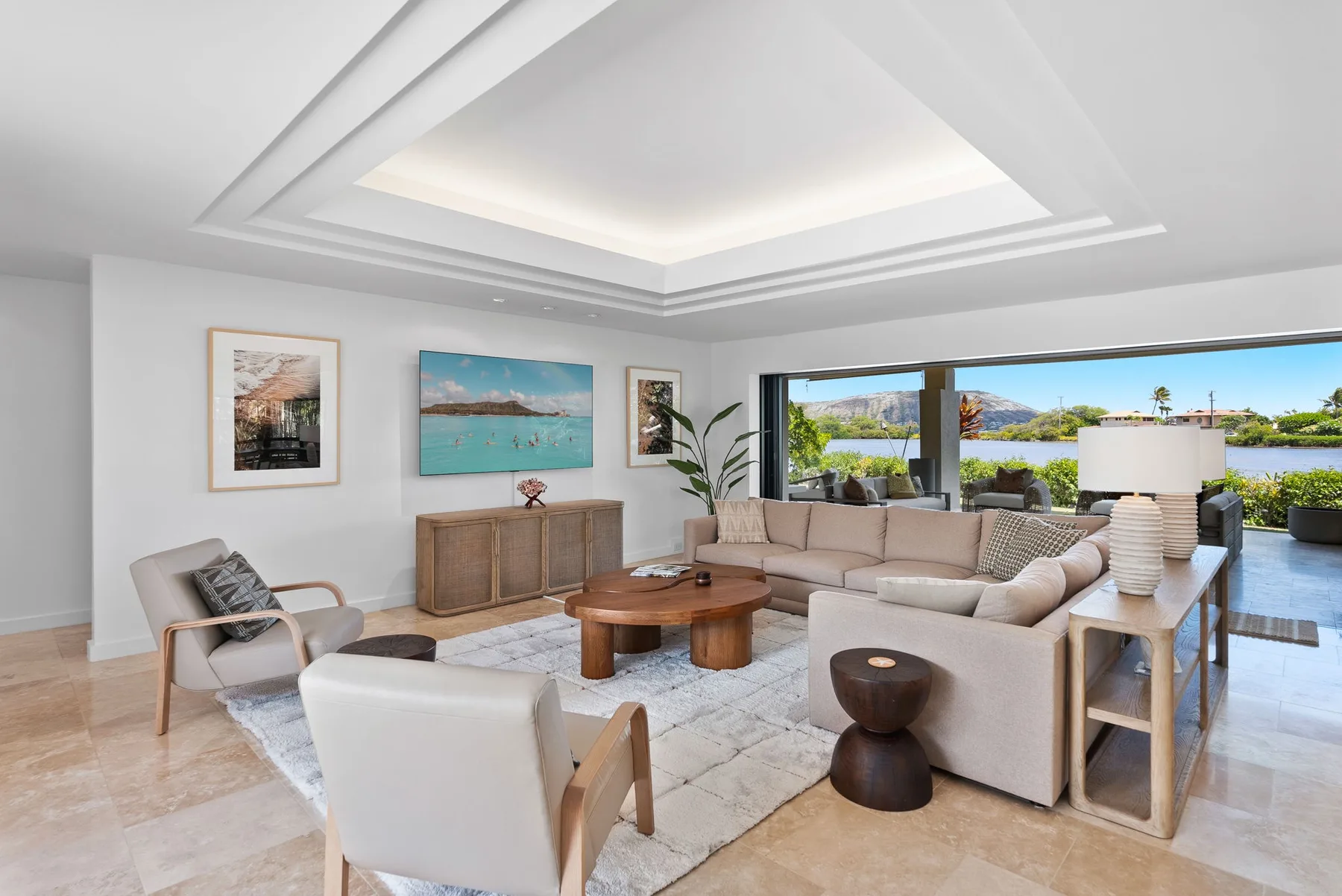 A bright living room with seating, a coffee table, and large windows overlooking the water.