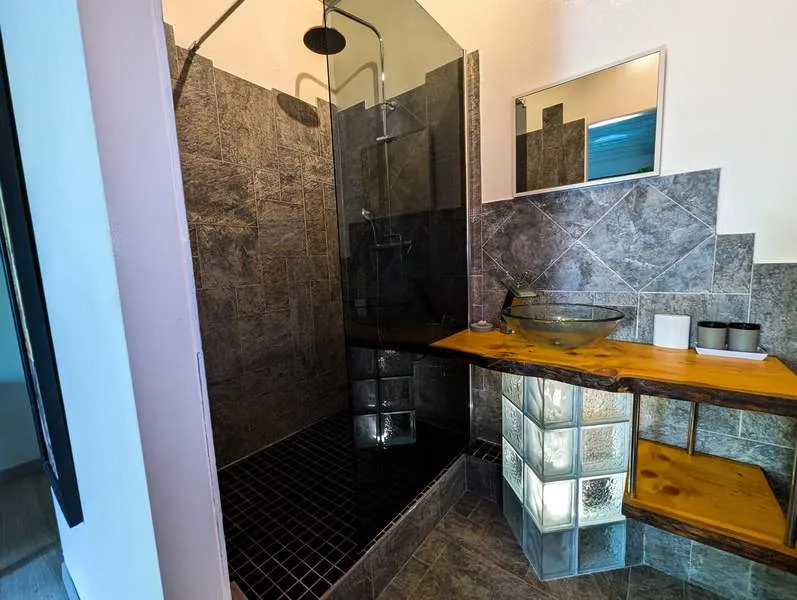 Baño privado con ducha a ras de suelo y lavabo de vidrio