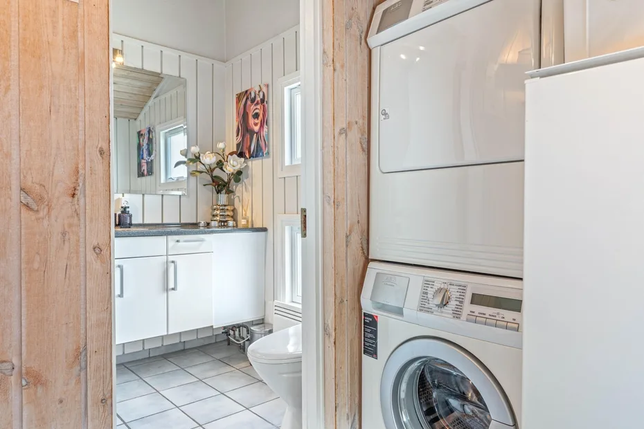 Se ven un lavabo y un inodoro junto a una zona de lavandería con una lavadora.